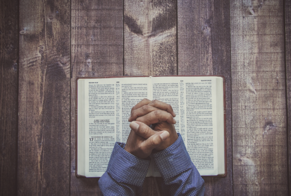 Praying hands above a bible